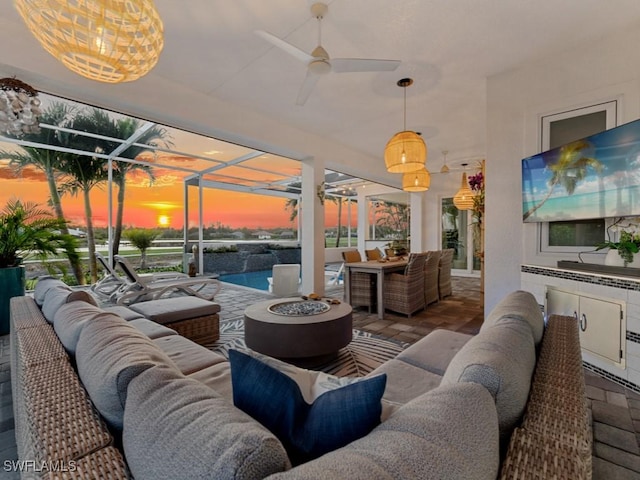 view of patio with a lanai, area for grilling, an outdoor living space with a fire pit, and a ceiling fan