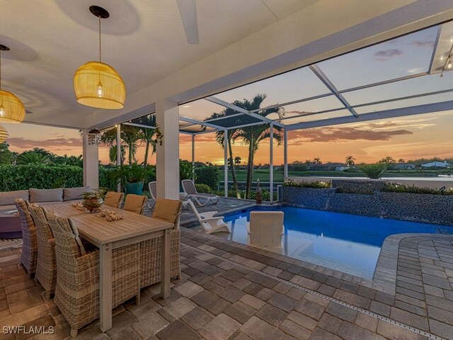 pool at dusk with outdoor dining space, a patio, an outdoor pool, and a lanai