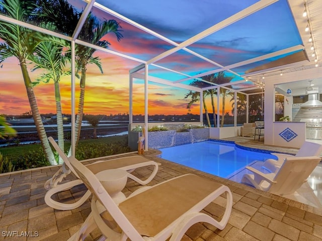 pool at dusk featuring glass enclosure, a patio, area for grilling, and an outdoor pool