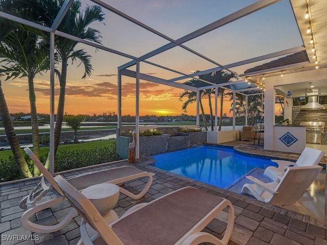 outdoor pool featuring glass enclosure, a patio, and area for grilling