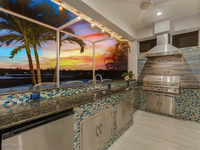 patio terrace at dusk featuring a sink, grilling area, a lanai, and exterior kitchen