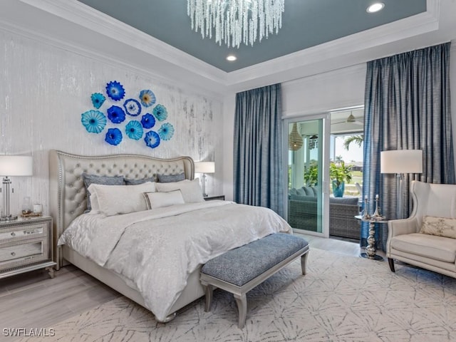 bedroom featuring access to exterior, wood finished floors, a raised ceiling, and ornamental molding