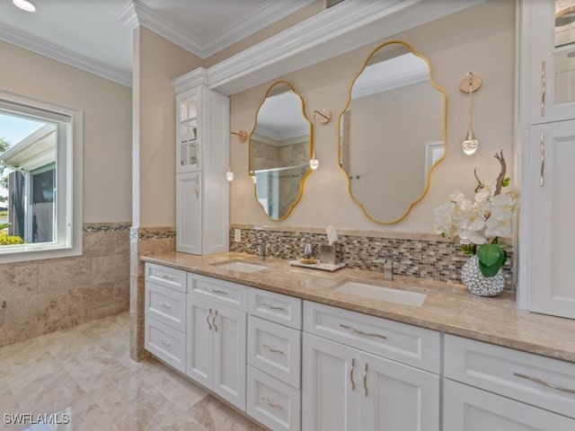 bathroom with a sink, tile walls, double vanity, and crown molding