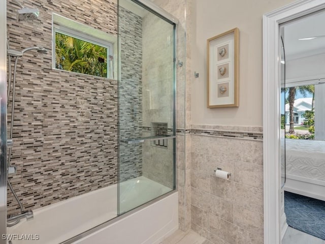 ensuite bathroom featuring ensuite bath, a wainscoted wall, tile walls, and shower / bath combination with glass door