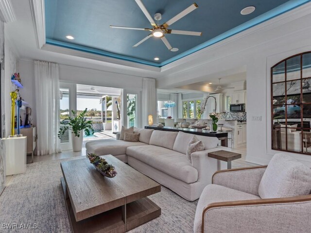 living area with a wealth of natural light, a tray ceiling, and ceiling fan