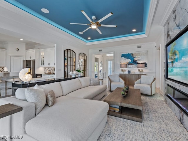 living room featuring a raised ceiling, recessed lighting, crown molding, and ceiling fan