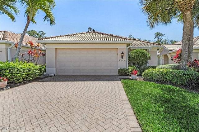 view of front of property with stucco siding, an attached garage, a tile roof, and decorative driveway