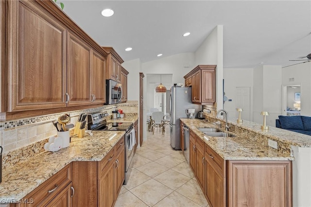 kitchen with brown cabinets, a sink, appliances with stainless steel finishes, a peninsula, and light stone countertops