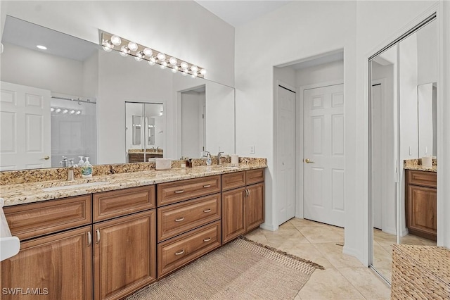 full bathroom with double vanity, tile patterned floors, and a sink