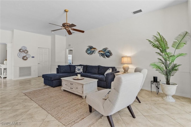 living room with a towering ceiling, visible vents, ceiling fan, and light tile patterned flooring