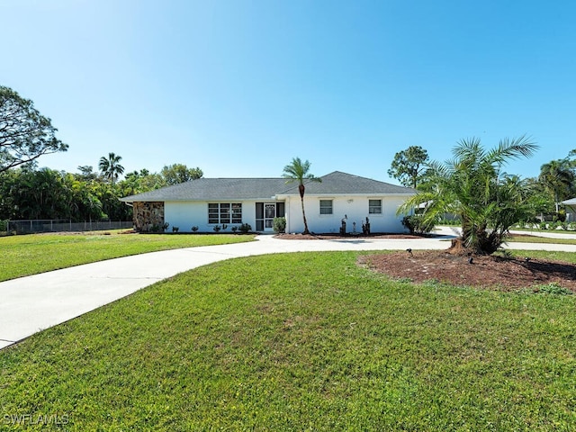 single story home with concrete driveway, fence, and a front yard