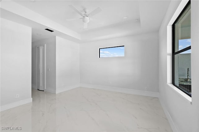 unfurnished room with visible vents, marble finish floor, baseboards, and a tray ceiling