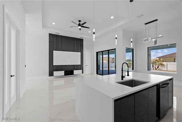 kitchen with a sink, a tray ceiling, marble finish floor, modern cabinets, and dark cabinets