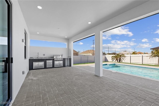 view of pool with area for grilling and a sink