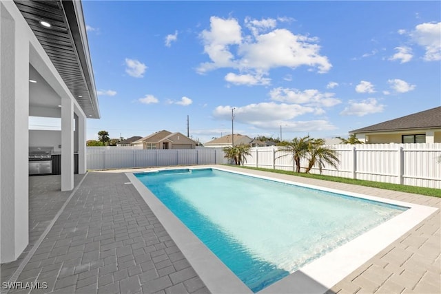 view of swimming pool featuring a patio, a fenced backyard, a fenced in pool, and grilling area