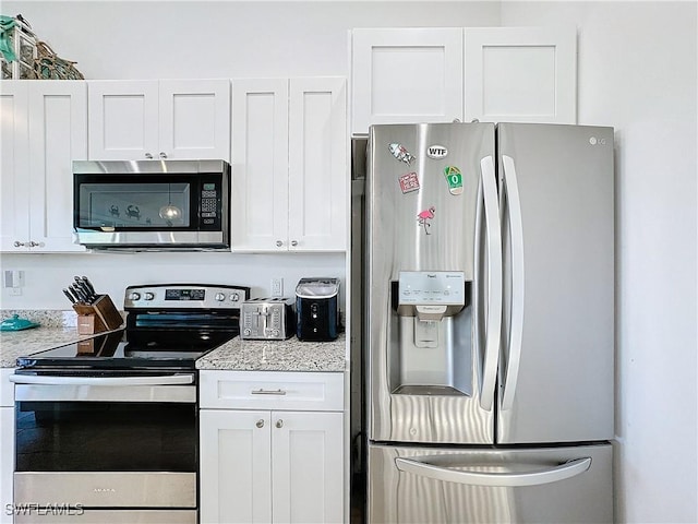 kitchen with light stone counters, white cabinets, and stainless steel appliances