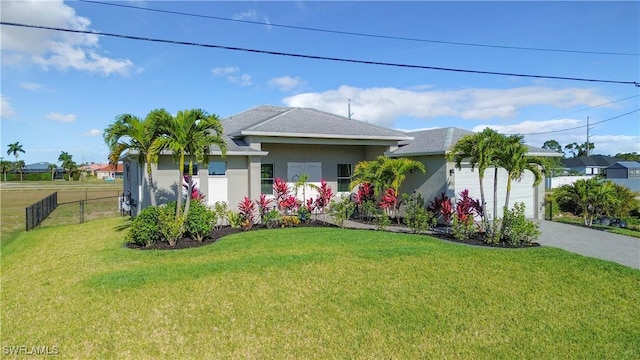 single story home featuring fence, a front yard, stucco siding, a garage, and driveway