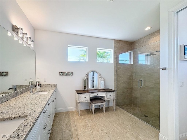 bathroom featuring double vanity, baseboards, a stall shower, and a sink