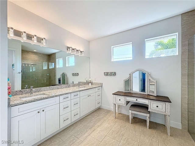 bathroom with double vanity, a stall shower, baseboards, and a sink