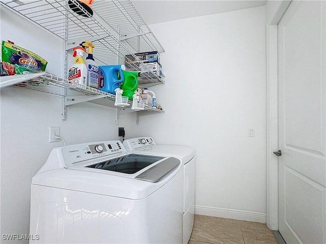 clothes washing area featuring washer and clothes dryer, laundry area, and baseboards