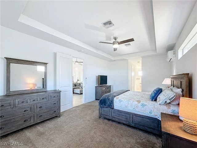 bedroom featuring a tray ceiling, a wall mounted air conditioner, visible vents, and carpet floors