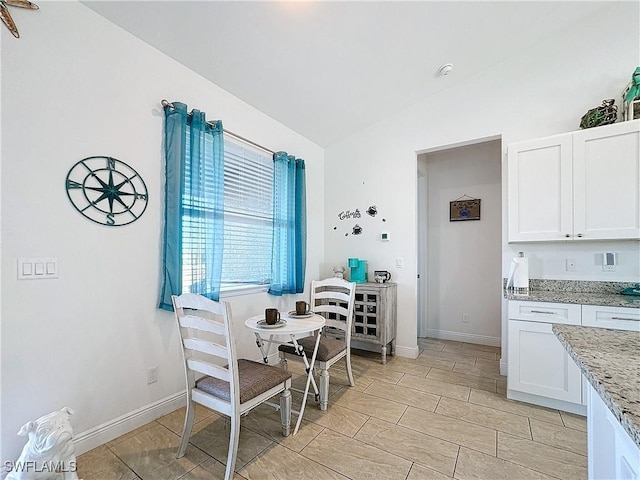 dining space with baseboards and vaulted ceiling