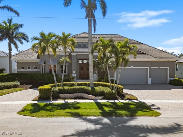 view of front of house featuring stucco siding, decorative driveway, and a garage