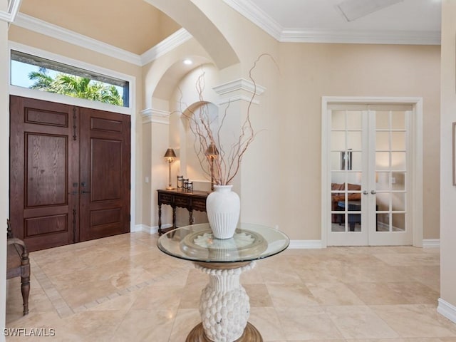 foyer with crown molding, french doors, baseboards, and arched walkways