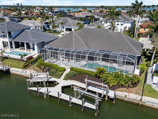 rear view of property featuring a water view, a tile roof, a residential view, boat lift, and a lanai