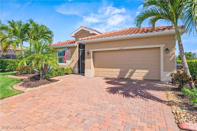 mediterranean / spanish house featuring stucco siding, decorative driveway, an attached garage, and a tile roof