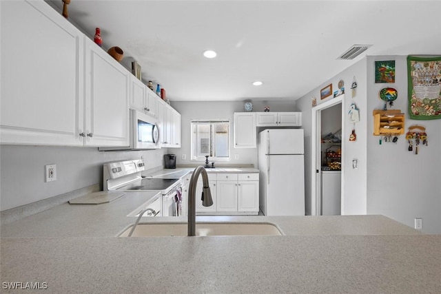 kitchen featuring visible vents, light countertops, white cabinets, white appliances, and a sink