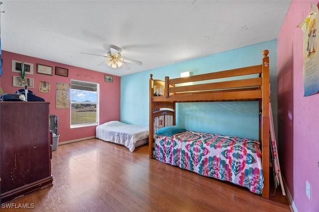 bedroom featuring baseboards, wood finished floors, and a ceiling fan