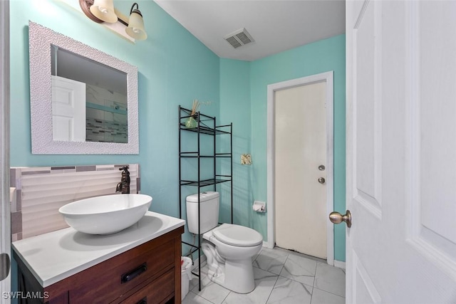 bathroom with visible vents, toilet, vanity, and marble finish floor