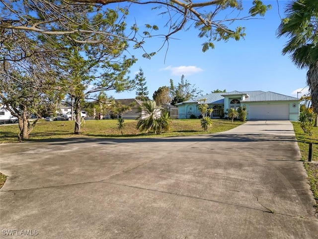 view of front of house with a front lawn, an attached garage, driveway, and metal roof