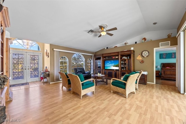 living area featuring visible vents, light wood-style flooring, ceiling fan with notable chandelier, french doors, and vaulted ceiling