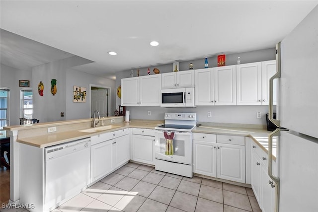 kitchen with white appliances, white cabinets, a peninsula, and a sink