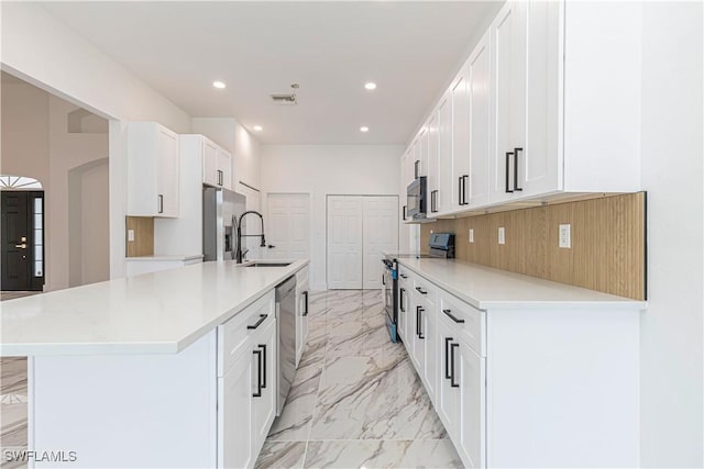 kitchen with recessed lighting, a sink, light countertops, appliances with stainless steel finishes, and marble finish floor