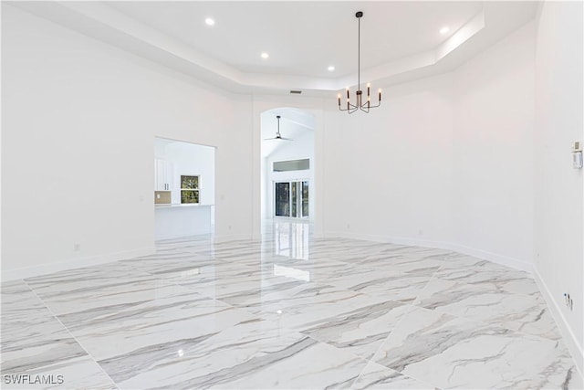 empty room featuring recessed lighting, a raised ceiling, and baseboards