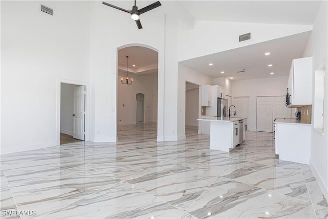 unfurnished living room featuring visible vents, arched walkways, marble finish floor, and a ceiling fan