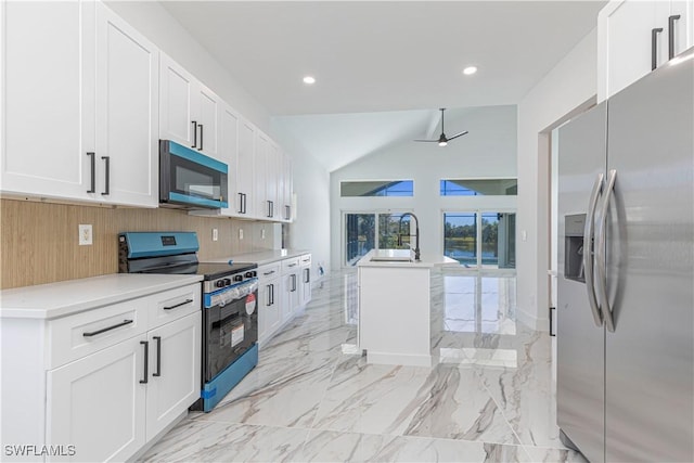 kitchen featuring marble finish floor, a center island with sink, a sink, white cabinetry, and appliances with stainless steel finishes