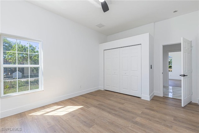 unfurnished bedroom featuring a closet, ceiling fan, baseboards, and light wood-style floors