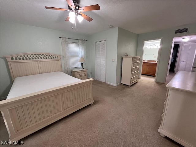 bedroom with baseboards, visible vents, a closet, ensuite bathroom, and light carpet