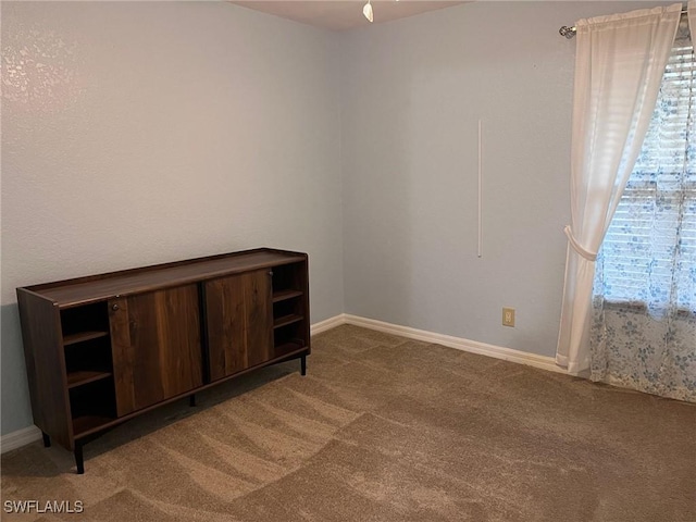 spare room featuring light colored carpet and baseboards