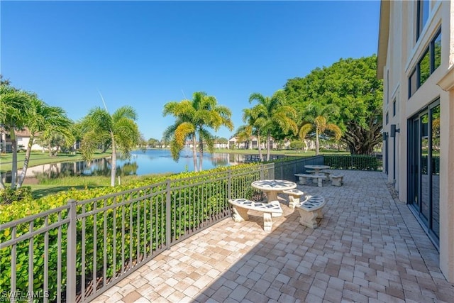 view of patio / terrace featuring fence and a water view