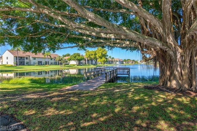 view of dock with a yard and a water view