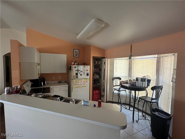 kitchen featuring light countertops, vaulted ceiling, light tile patterned floors, a peninsula, and white appliances