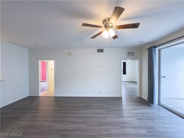 spare room featuring wood finished floors, a ceiling fan, visible vents, and a textured ceiling