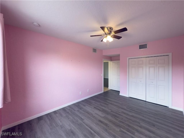 unfurnished bedroom featuring visible vents, baseboards, a closet, and dark wood finished floors