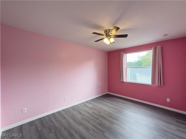 spare room with a ceiling fan, wood finished floors, baseboards, and a textured ceiling