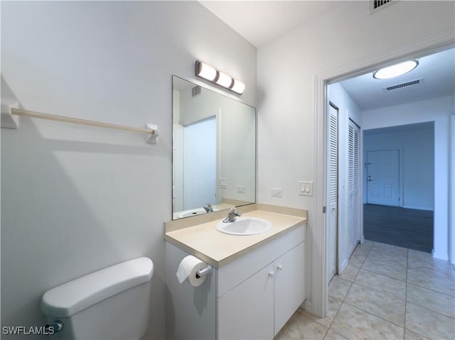 bathroom featuring tile patterned floors, visible vents, toilet, a closet, and vanity